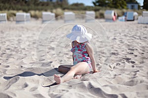 Little girl on white sand beach enjoying summer, sun and vacation