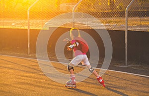 little girl in white shorts and a pink T-shirt is skating on the role of kah at sunset.