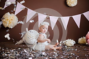 Little girl in a white suit on a brown chocolate background celebrates her birthday