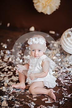 Little girl in a white suit on a brown chocolate background celebrates her birthday