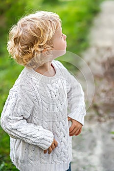 A little girl in a white sweater looks up in surprise. Children& x27;s emotions. Portrait of a little 4-year-old girl