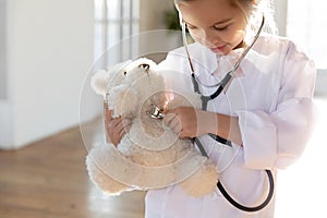 Little girl in white uniform examine plush toy