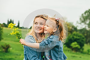 Little girl with wildflowers hugs mom