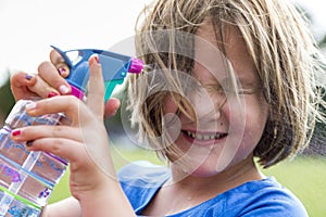 Little girl wincing as she sprays water on her face to cool off photo