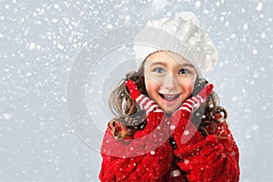 Little girl in winter clothing, think about Santa. Snow background