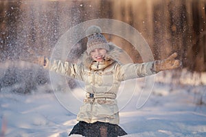 Little girl in the winter park. Girl enjoys snowing in the forest