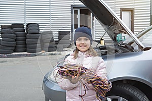 Little girl with wires on a background of a car. Car service