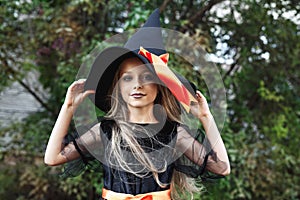 Little girl in witch costume outdoor. Happy Halloween