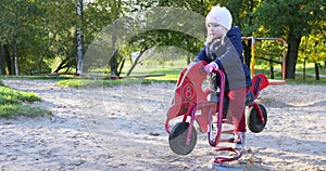 Little girl on wooden motorbike playing on playgrou