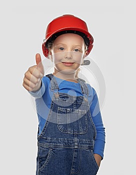 Little girl worker in a safety helmet with a tool.