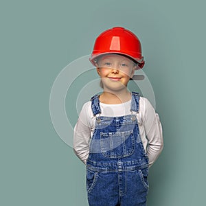 Little girl worker in a safety helmet with a tool.