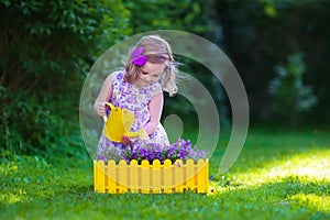 Little girl working in the garden watering flowers