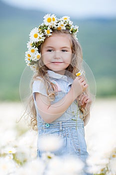 Little girl in a wreath of white daisies