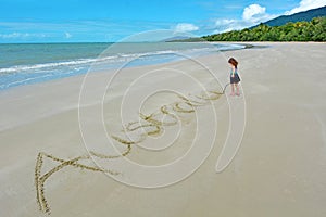 Little girl write the word Australia in the sand