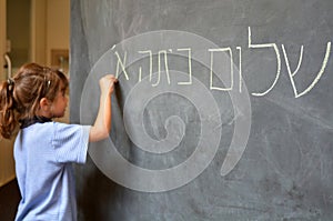 Little girl writes Hello First Grade greetings in Hebrew photo