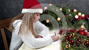 Little girl writes a letter to santa claus. Emotions: joy, happiness, thoughtfulness, fatigue... Christmas should be hurried soon