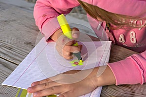 Little girl writes in a notebook on the nature