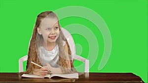 Little girl writes to writing-book on a Green Screen, Chroma Key