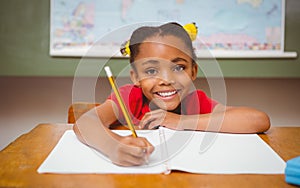 Little girl writing book in classroom