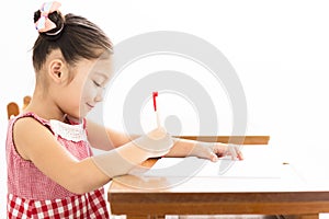 little girl writing at desk in classroom