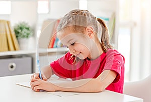 Little girl writing in notebook with pen