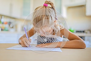 Little girl writing with pen in notebook