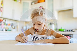 Little girl writing with pen in notebook