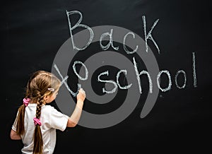 Little girl wrote in chalk on black chalkboard