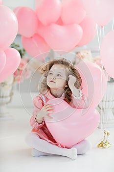 Cute six year old girl in pink dress with pink balloons in the shape of heart
