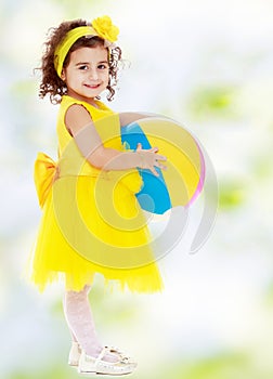 Little girl in yellow dress with big ball