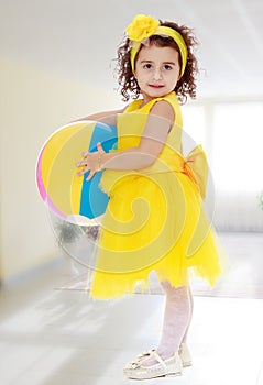 Little girl in yellow dress holding a ball