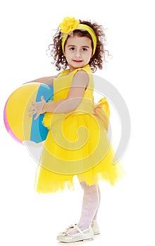 Little girl in yellow dress holding a ball