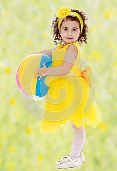 Little girl in yellow dress holding a ball