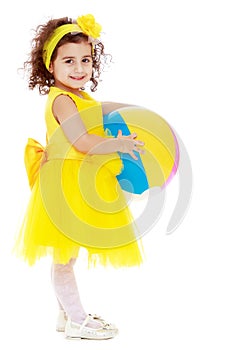 Little girl in yellow dress holding a ball