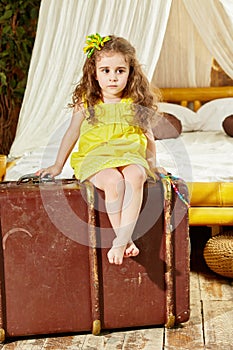 Little girl in yellow dress sits on old big ragged photo