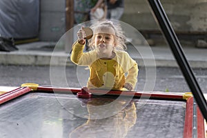 little girl in a yellow jacket plays air hockey