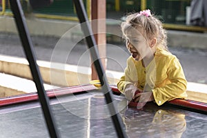 little girl in a yellow jacket plays air hockey