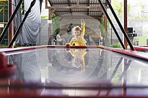 little girl in a yellow jacket plays air hockey