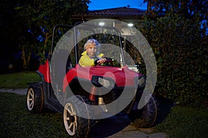 Little girl in yellow jacket sits in red buggy car photo