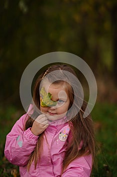 Little girl with yellow leaf. Child playing with autumn golden leaves. Kids play outdoors in the park. Children hiking