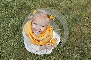 Little girl in a yellow scarf and with yellow flowers