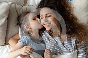 Little girl and young mom relax in cozy bed