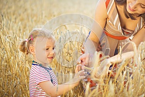 Little girl with young mother at grain wheat field