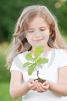 Little girl and young oak tree