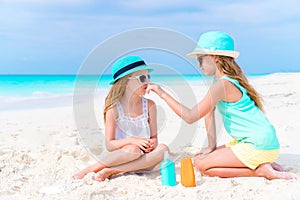 Little girls applying sun cream to each other on the beach. The concept of protection from ultraviolet radiation