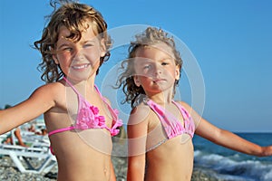 Little girls on beach, placed hands in sides