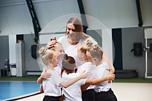 Little girls, beginner gymnastics athletes doing exercises with gymnastics equipment at sports gym, indoors. Concept of