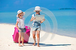 Little girls with big suitcase and map at tropical