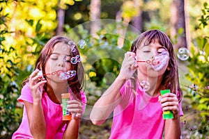 Little girls blowing bubbles with the wand in the park
