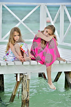 Little girls in colorful dress on the white wooden pier